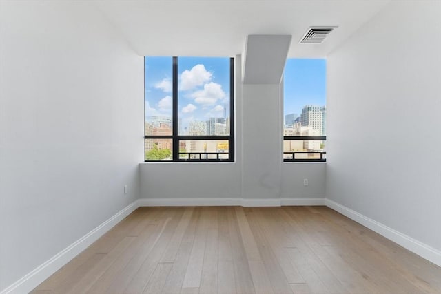 empty room with wood finished floors, a view of city, and baseboards
