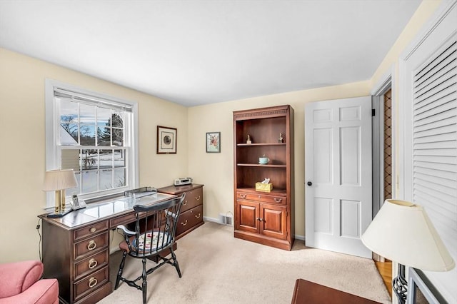 office space featuring baseboards, visible vents, and light colored carpet