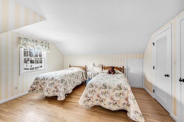 bedroom with vaulted ceiling, baseboards, hardwood / wood-style flooring, and wallpapered walls