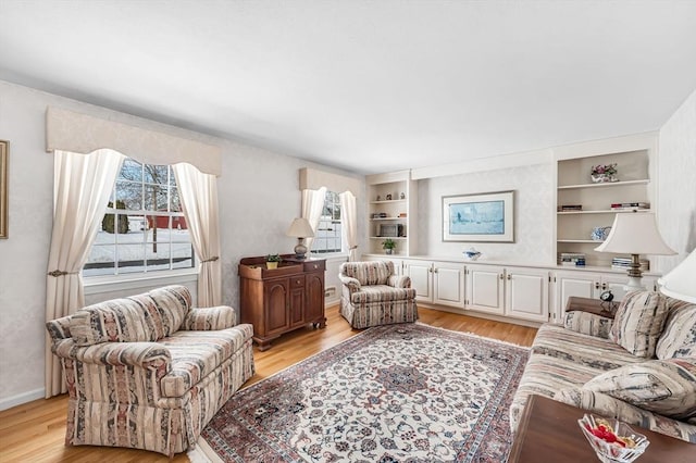 living room featuring built in features, light wood-type flooring, and baseboards