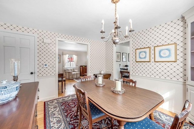 dining space featuring light wood-type flooring, a notable chandelier, and wallpapered walls