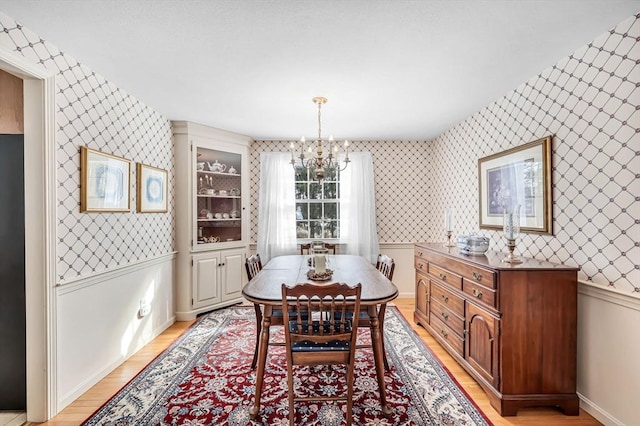 dining area with light wood-type flooring, wallpapered walls, baseboards, and a chandelier