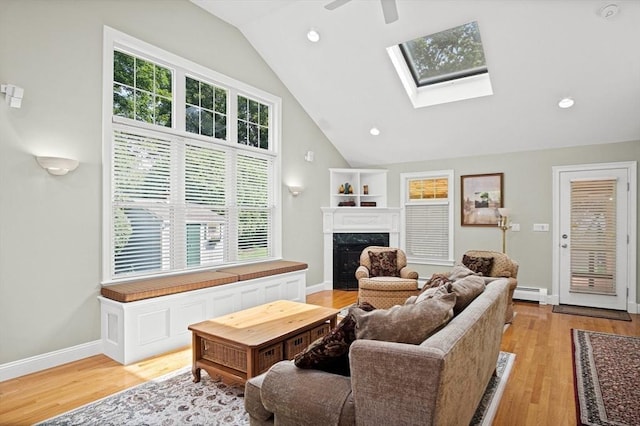 2 Christin Way, Woburn, MA 01801 - living area featuring a baseboard heating unit, vaulted ceiling, a skylight, a premium fireplace, and light wood-type flooring