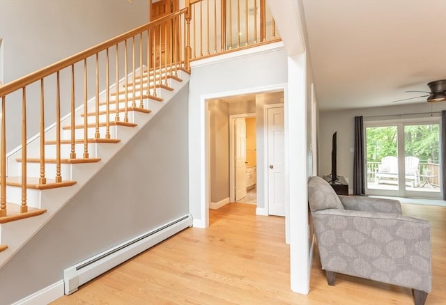 16 Austin Ln, Acushnet, MA 02743 - stairway featuring a baseboard heating unit, wood finished floors, a ceiling fan, baseboards, and a wood stove