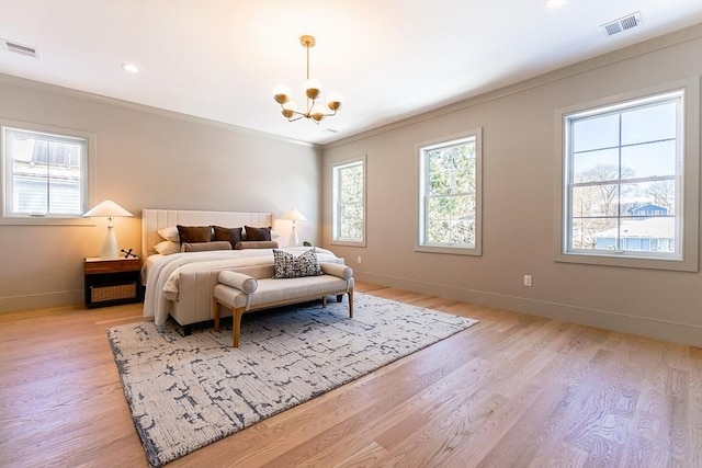 bedroom featuring an inviting chandelier, ornamental molding, and light wood-type flooring