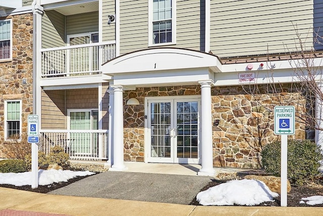 entrance to property featuring stone siding, french doors, and a porch