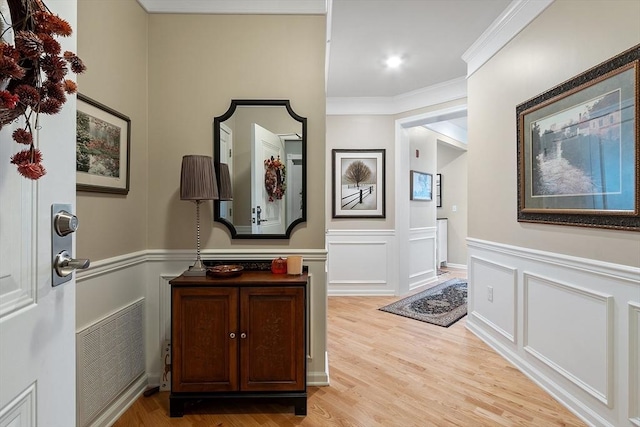 interior space with ornamental molding, visible vents, a decorative wall, and light wood-style flooring