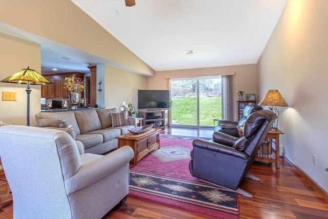 living area with baseboards, visible vents, wood finished floors, and lofted ceiling