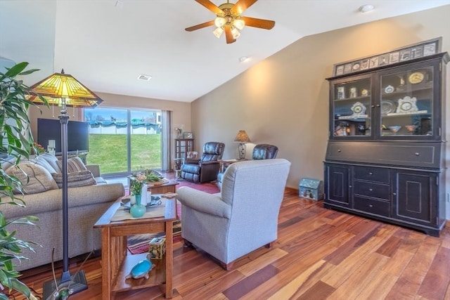 living room featuring light wood-style floors, a ceiling fan, lofted ceiling, and visible vents