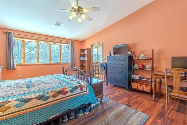 bedroom with ceiling fan, vaulted ceiling, wood finished floors, and visible vents