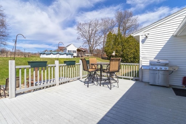 wooden deck with grilling area, a lawn, and outdoor dining area
