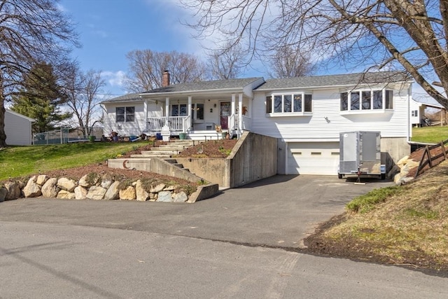 single story home featuring a front lawn, a chimney, an attached garage, driveway, and a porch