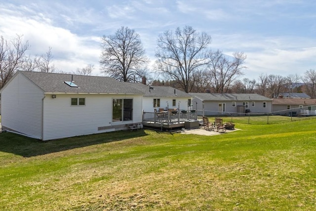 rear view of house featuring a fire pit, a wooden deck, a yard, and fence