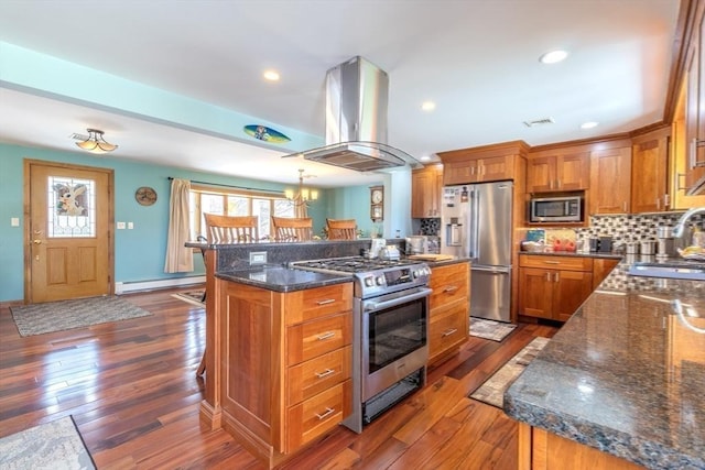 kitchen featuring dark wood-style flooring, brown cabinetry, stainless steel appliances, island exhaust hood, and a baseboard radiator