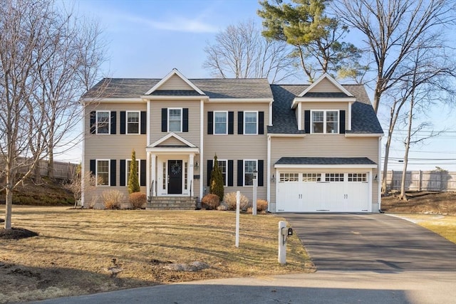 view of front of house with aphalt driveway, an attached garage, and a shingled roof