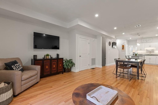 living area with visible vents, recessed lighting, light wood-style flooring, and baseboards