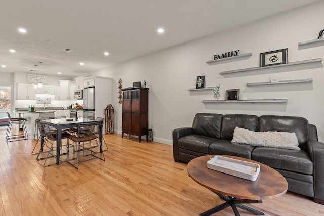 living room featuring recessed lighting, baseboards, visible vents, and light wood-type flooring