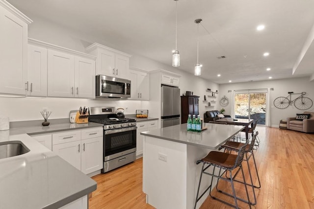 kitchen featuring white cabinets, appliances with stainless steel finishes, a center island, recessed lighting, and open floor plan