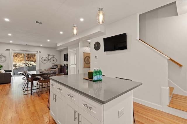 kitchen with a kitchen island, white cabinets, open floor plan, light wood-style floors, and recessed lighting