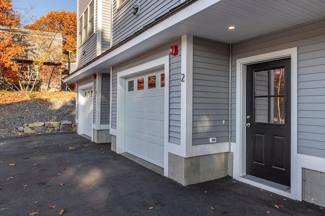 property entrance with a garage and aphalt driveway