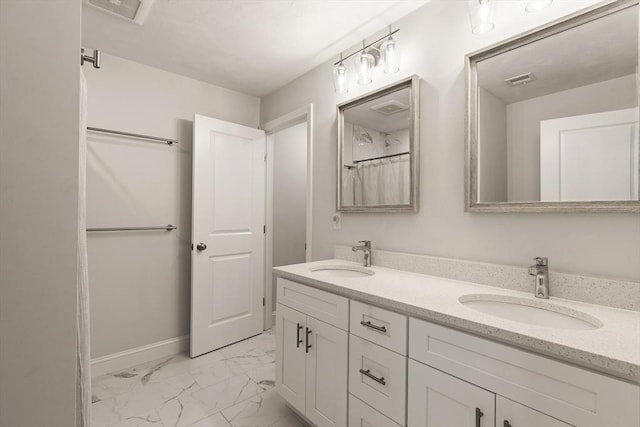 bathroom featuring double vanity, a sink, marble finish floor, and baseboards