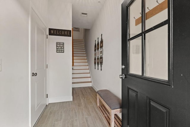 interior space featuring light wood-style floors, baseboards, stairway, and visible vents