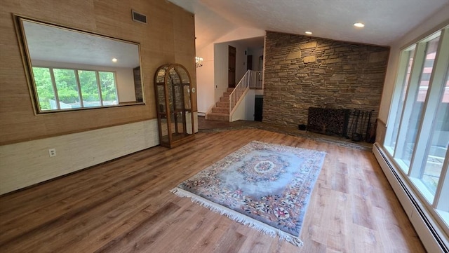 17 Crowningshield Dr, Paxton, MA 01612 - unfurnished living room with a baseboard radiator, vaulted ceiling, stairs, wood finished floors, and a stone fireplace