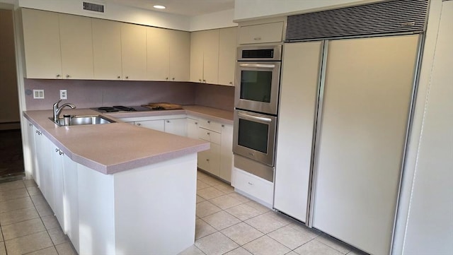 17 Crowningshield Dr, Paxton, MA 01612 - kitchen with paneled built in fridge, stainless steel double oven, a peninsula, light tile patterned flooring, and light countertops
