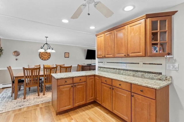 87 Lockwood Rd, Lynn, MA 01904 - kitchen with light wood-style floors, baseboard heating, light stone counters, brown cabinets, and glass insert cabinets