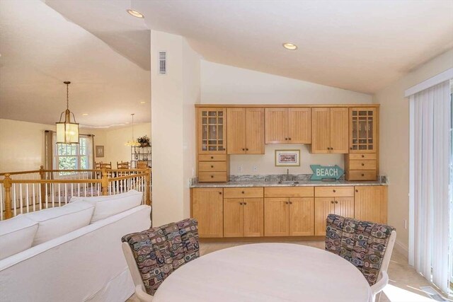 kitchen with lofted ceiling, visible vents, glass insert cabinets, and a sink