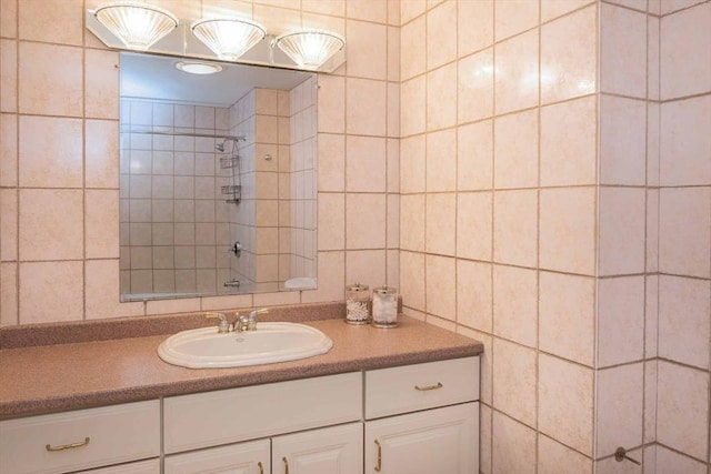 full bath featuring a tile shower, tile walls, and vanity