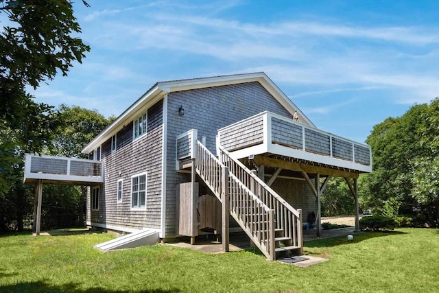 back of property featuring a deck, a yard, and stairs