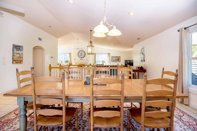 dining area featuring vaulted ceiling, light tile patterned flooring, arched walkways, and a wealth of natural light