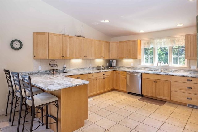 kitchen with a sink, a peninsula, stainless steel dishwasher, and light brown cabinetry