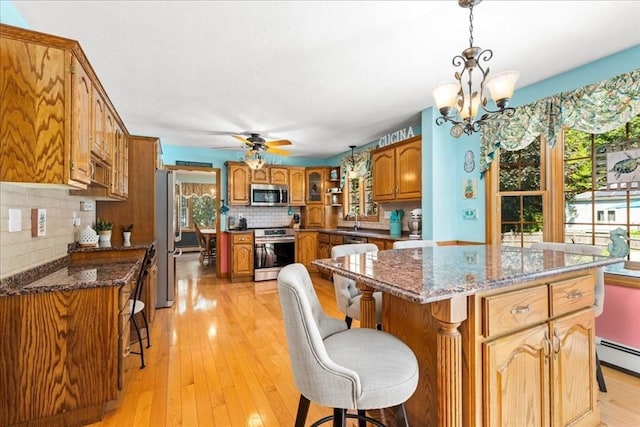 27 Crestview Dr, Uxbridge, MA 01569 - kitchen featuring appliances with stainless steel finishes, brown cabinets, decorative backsplash, a kitchen bar, and a chandelier