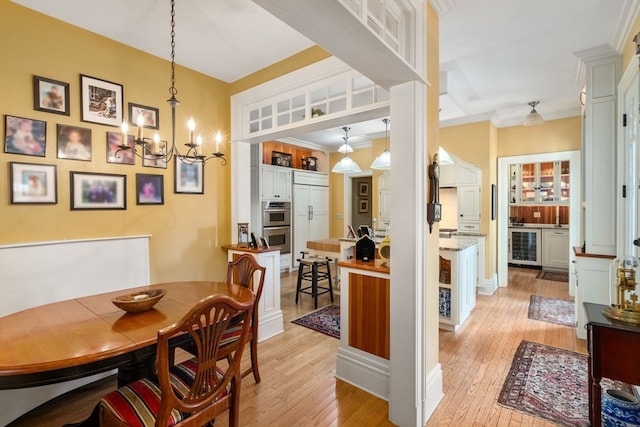 dining space with light hardwood / wood-style flooring, wine cooler, an inviting chandelier, and crown molding