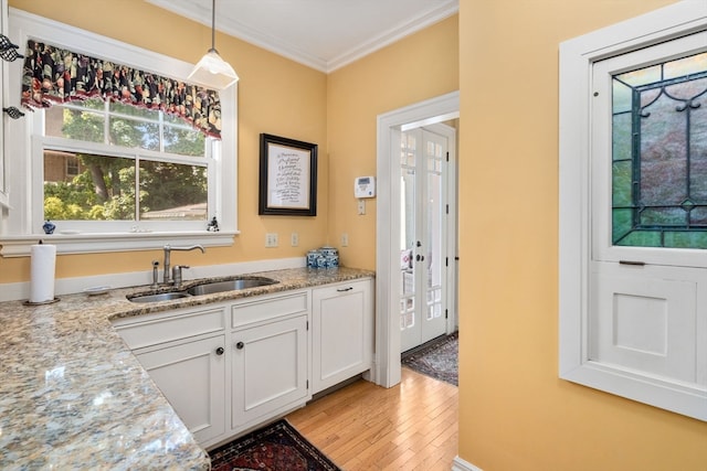 kitchen featuring pendant lighting, light wood-type flooring, white cabinets, and light stone countertops