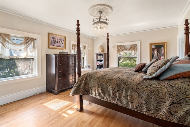 bedroom with crown molding, light hardwood / wood-style floors, and a notable chandelier