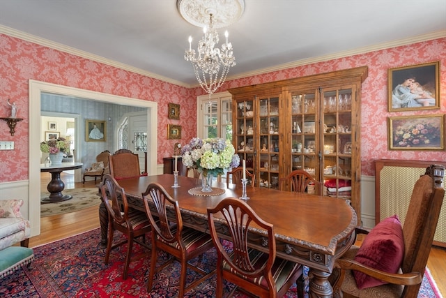 dining area with wood-type flooring, a notable chandelier, and ornamental molding