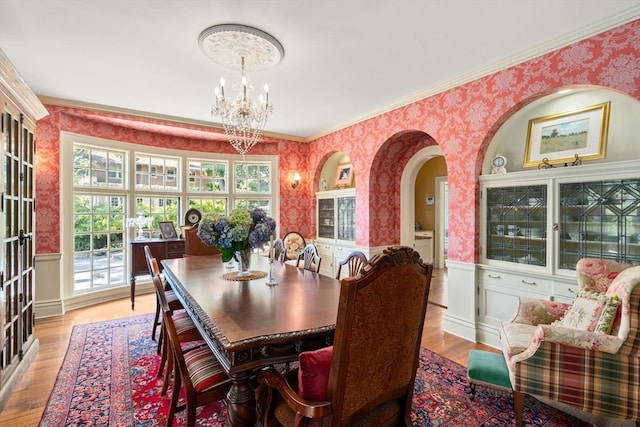 dining room featuring crown molding, light hardwood / wood-style flooring, and a notable chandelier