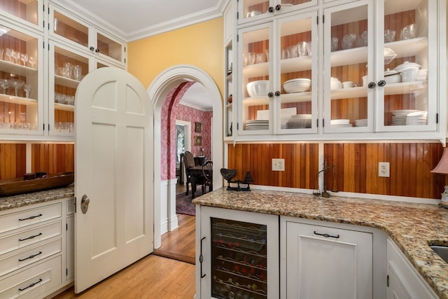 bar featuring light wood-type flooring, wine cooler, light stone counters, and white cabinetry