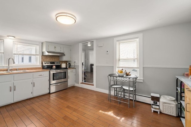 kitchen with stainless steel electric stove, a baseboard heating unit, white cabinetry, a sink, and under cabinet range hood