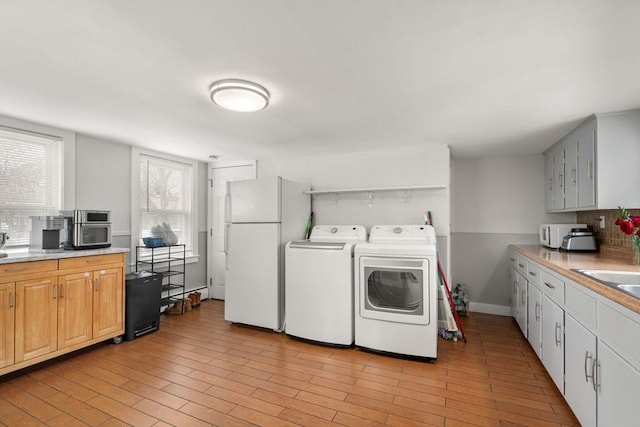 kitchen with light countertops, washing machine and clothes dryer, freestanding refrigerator, and white cabinetry