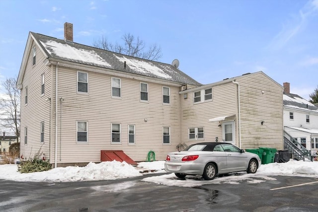 snow covered house featuring a chimney