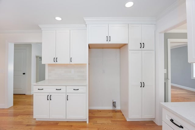 100 King St, Groveland, MA 01834 - kitchen featuring white cabinetry, light wood-type flooring, light countertops, ornamental molding, and tasteful backsplash