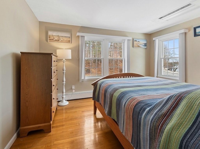 bedroom with light wood-type flooring, a baseboard radiator, and baseboards