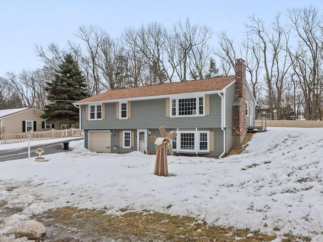 colonial-style house with fence, a chimney, and an attached garage