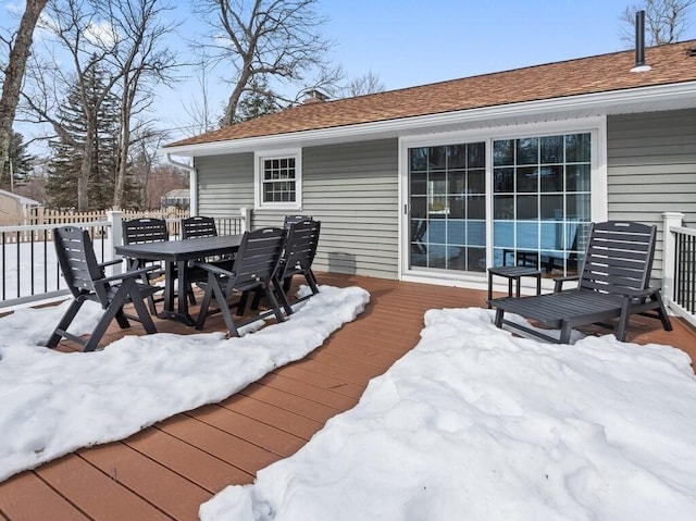 snow covered deck featuring outdoor dining area and fence