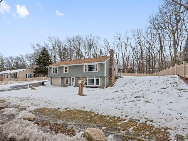 view of front of property featuring an attached garage, a chimney, and fence