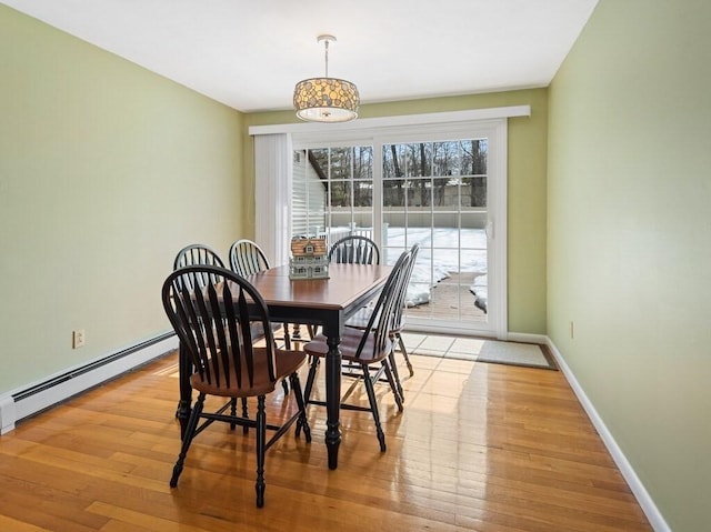 dining space with baseboard heating, light wood-type flooring, and baseboards